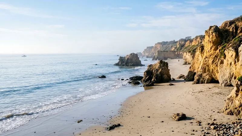 Malibu beach with sea stacks, golden cliffs and calm ocean in morning haze